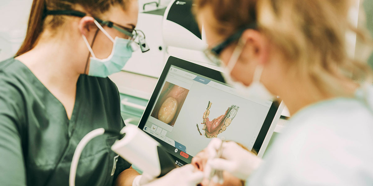 Zahnärztin Ricarda Richter im Zahnzentrum Hanau vor einem Computerbildschirm. Sie scannt mit einem Intraoralscanner die Zähne eines Patienten.