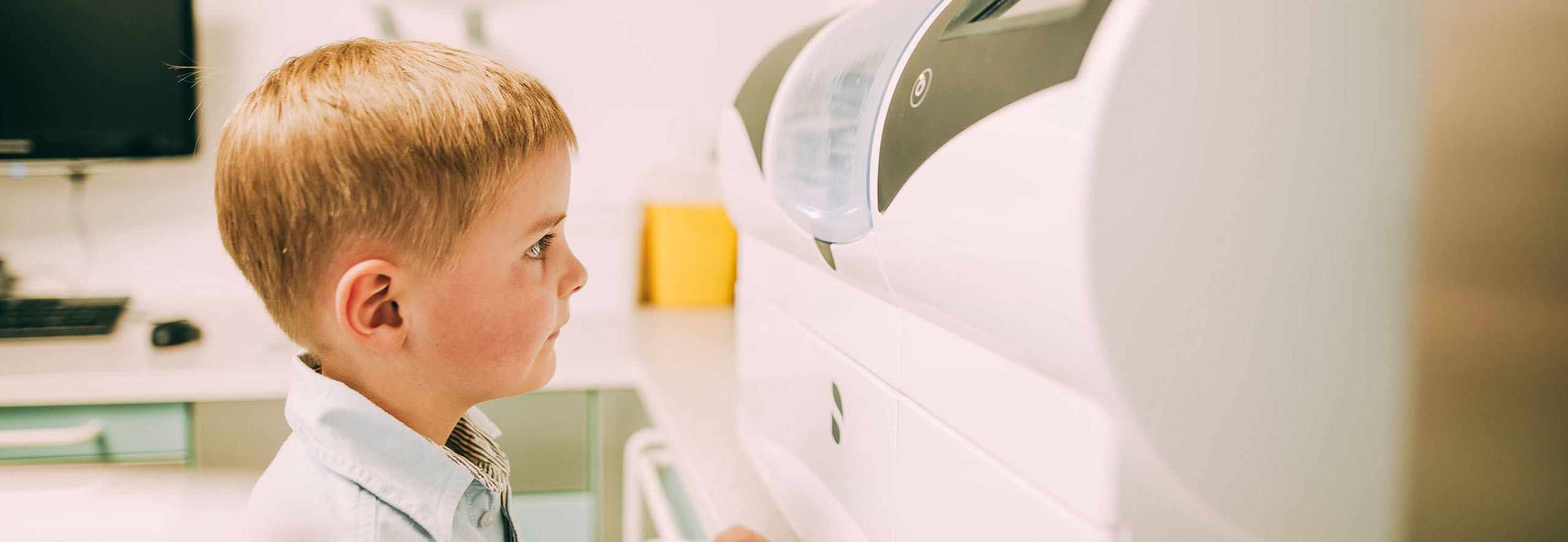 Ein Junge , etwa 8 Jahre alt, blickt in die Cerec-Maschine und ist fasziniert vom präzisen Fräsen der Cerec-Maschine.
