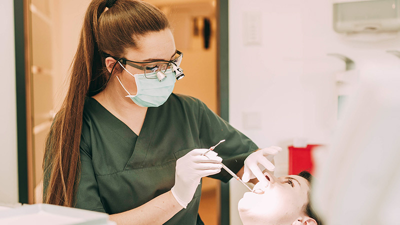 Zahnärztin Ricarda Richter blickt in ihrer Zahnarztpraxis in Hanau in den Mund einer Patientin.