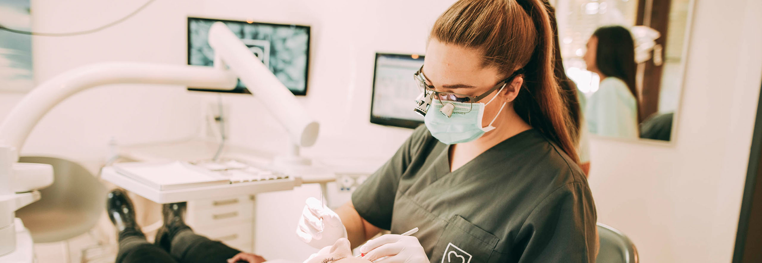 Zahnärztin Ricarda Richter behandelt die Wurzel eines Patienten und blickt dabei durch eine Lupenbrille.